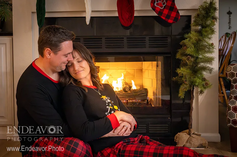 couple christmas photo shoot in front of fire place in fort collins